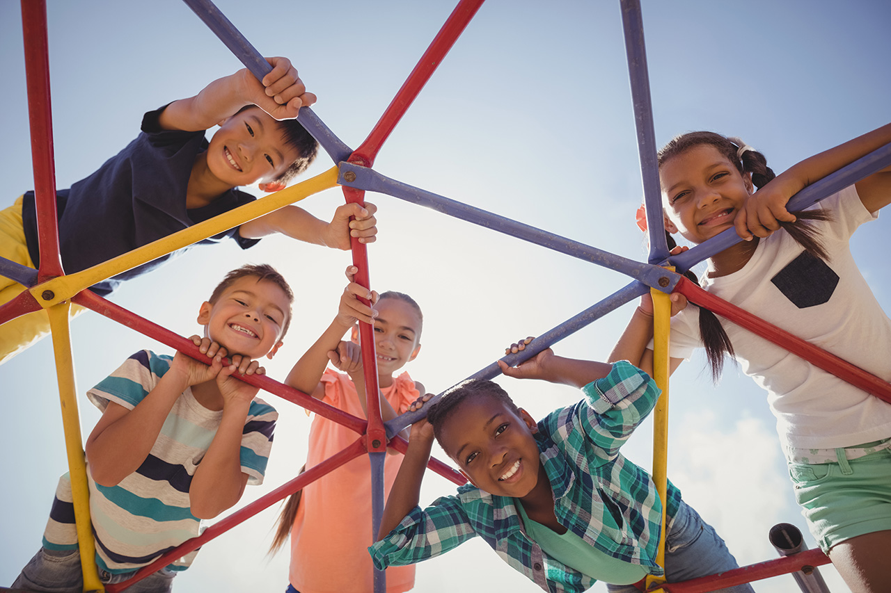 portrait of happy schoolkids looking through dome climber